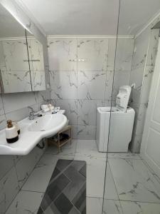 a white bathroom with a sink and a toilet at JET, luxury appartment 20m from the beach in Kini