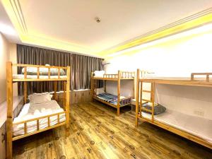 a room with three bunk beds and wooden floors at Fusion Hotel in Sihanoukville