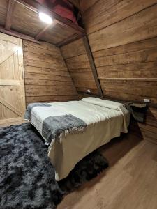Chalets Vistas del Poas في هيريديا: غرفة نوم بسرير في كابينة خشبية