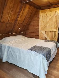 Chalets Vistas del Poas في هيريديا: سرير في غرفة ذات سقف خشبي