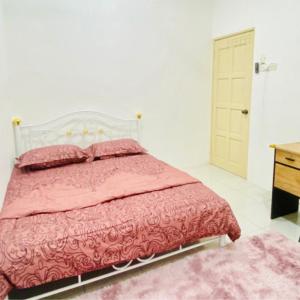a bedroom with a pink bed and a wooden dresser at Nuria Padang Serai Homestay in Padang Serai