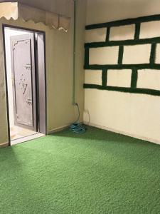 um quarto com um piso verde e uma parede de tijolos em Lama em Riyadh