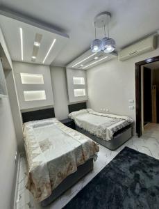 a bedroom with two beds and a chandelier at Porto elsokhna pyramids VIP in ‘Atāqah