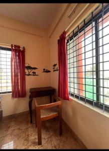 um quarto com uma mesa, uma cadeira e janelas em Serviced apartment with WiFi parking kitchen etc em Bangalore