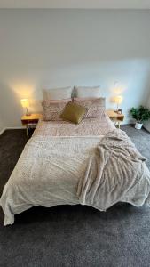 基督城的住宿－CBD Luxury 2 Bedroom Retreat，卧室内的一张大床,配有两盏灯