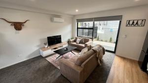 a living room with a couch and a tv at CBD Luxury 2 Bedroom Retreat in Christchurch