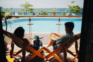 a man and a woman sitting in chairs next to a swimming pool at W Golf Resort in Oslob