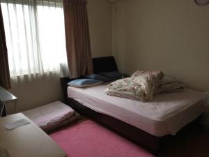 een kleine slaapkamer met 2 bedden en een raam bij ichihara homestay-stay with Japanese family - Vacation STAY 15787 in Ichihara