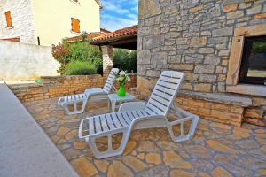 twee witte stoelen en een tafel op een stenen patio bij Ferienhaus mit Privatpool für 6 Personen ca 100 qm in Svetvincenat, Istrien Binnenland von Istrien in Svetvinčenat