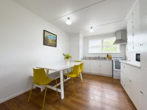 a kitchen with a white table and yellow chairs at Serene Home in Whangarei in Whangarei