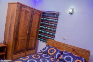 1 dormitorio con cama de madera y armario de madera en One bedroom oluwa-sheyi-apartment, en Cotonou
