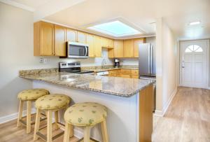 a kitchen with a large island with two stools at Breakers West C1 condo in Sanibel