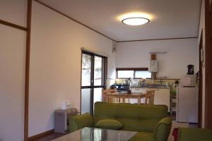 高山的住宿－Komorebi/こもれび，一间带绿色沙发的客厅和一间厨房
