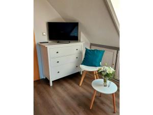 a room with a dresser with a tv and a chair at on the Werraufer Modern retreat 