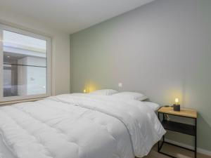 a bedroom with a large white bed and a window at Corner apartment in the center with 3 bedrooms in Middelkerke