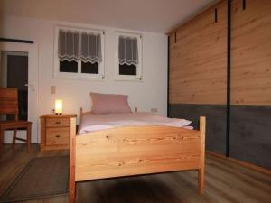 a bedroom with a bed with a wooden frame and two windows at Townhouse Modern Retreat in Mellrichstadt