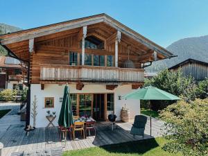 a wooden house with a balcony and an umbrella at Chalet Nordic Modern Retreat in Bayrischzell