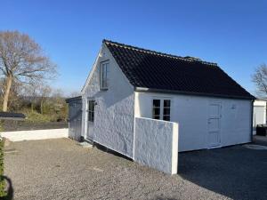 a small white building with a black roof at Ocean View Modern Retreat in Neksø