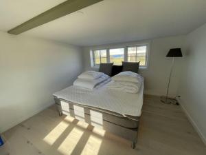 a bedroom with a bed with white sheets and a window at Ocean View Modern Retreat in Neksø