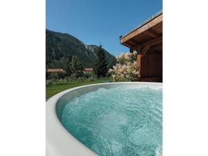 a bath tub filled with blue water next to a house at Chalet Nordic Modern Retreat in Bayrischzell