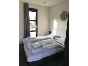 een slaapkamer met een bed met witte lakens en een raam bij Sonnenplätzchen in Enkhuizen