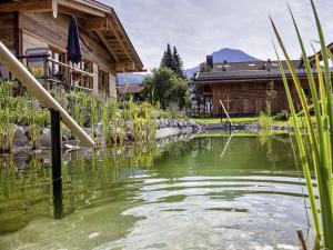 a pond in front of a building with a house at Alpglück Chalet Modern retreat in Oberstdorf