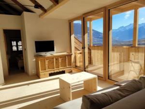 een woonkamer met een tv en een groot raam bij hoamisch Modern retreat in Malles Venosta