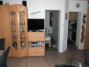 ein Wohnzimmer mit einem TV und einem hölzernen Entertainment-Center in der Unterkunft "Seestrasse" 24 Merchant in Horumersiel
