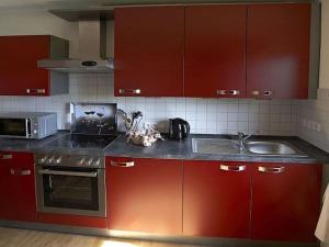 a kitchen with red cabinets and a sink at with tower Modern retreat in Scheinfeld