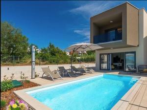 a swimming pool with chairs and an umbrella next to a house at Casa Esmeralda I in Novigrad Istria