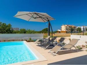 a group of chairs and an umbrella next to a swimming pool at Casa Esmeralda I in Novigrad Istria