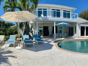a house with a pool and chairs and an umbrella at Villa Bayside Beach in Fort Myers Beach