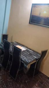 a dining room table with chairs and a picture on the wall at Oluwa-Sheyi Apartment in Ketou in Kétou