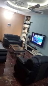 a living room with couches and a flat screen tv at Oluwa-Sheyi Apartment in Ketou in Kétou
