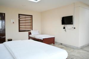 ein weißes Schlafzimmer mit einem Bett und einem TV in der Unterkunft Kalanad Residency in Kalanādu