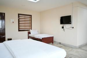a white bedroom with a bed and a tv at Kalanad Residency And Convention Centre in Kalanādu