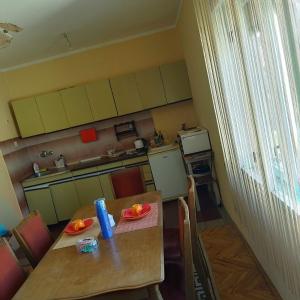 a small kitchen with a wooden table and a table and chairs at Prenoćište Zora 