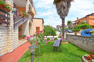 - un jardin avec un banc et des fleurs dans la cour dans l'établissement Ferienwohnung für 5 Personen ca 55 qm in Novigrad, Istrien Istrische Riviera, à Karpinjan