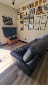 a black leather couch in a living room with a television at 135 On Seaview Parpaparaumu Beach in Paraparaumu