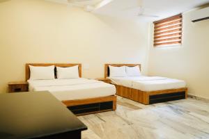 a room with two beds and a table at Kalanad Residency And Convention Centre in Kalanādu +34 photos