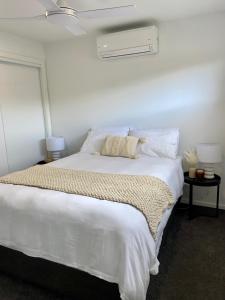 ein Schlafzimmer mit einem großen weißen Bett mit weißer Bettwäsche und Kissen in der Unterkunft Stunning Lakeside Villa in River Front Resort with Pool in Moama