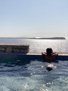 Ein Mann im Pool mit Blick auf das Wasser. in der Unterkunft Cave Suite in Sarakíniko