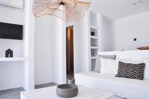 a white living room with a bed and a chandelier at Cave Suite in Sarakíniko