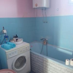 a bathroom with a washing machine and a bath tub at Prenoćište Zora 