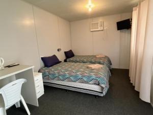 Habitación pequeña con 2 camas y escritorio. en Lyndhurst Hotel motel SA Australia 5731, en Mandurama