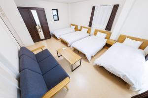 a room with two beds and a couch and a table at 5 minutes Shin-Osaka 3 in Osaka