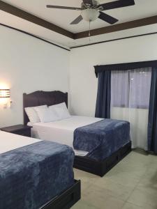Yamaranguila的住宿－Hotel Victoria Inn，一间卧室配有两张床和吊扇