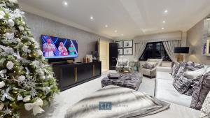 a living room with a christmas tree and a television at Grand London suburban mansion in Buckhurst Hill