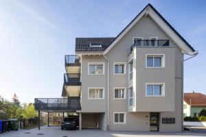 a tall white building with a balcony and a car at STAYY Flagship Limmattal - contactless check-in in Schlieren