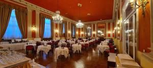 une salle de banquet avec des tables blanches, des chaises et des lustres dans l'établissement Grand Hotel De Londres, à Sanremo